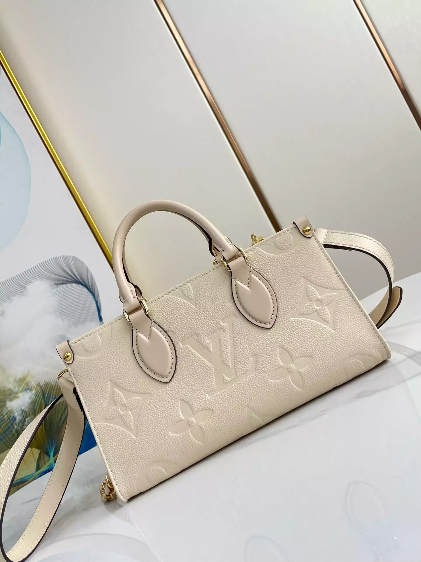OnTheGo East West Monogram Empreinte Creme Leather